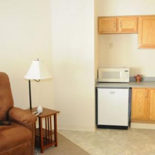 A small living space with a kitchenette featuring a mini fridge and microwave.
