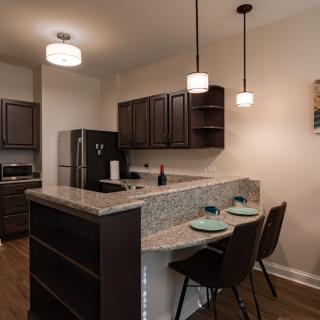 A modern kitchen with a breakfast bar, featuring pendant lighting and bar stools.