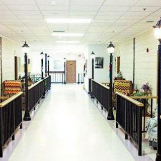 A bright, well-lit hallway with decorative lamps and railings, featuring furniture on both sides.