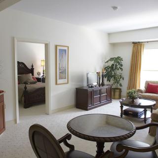 A cozy living room with elegant furniture and a view into the adjacent bedroom.