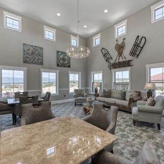 A spacious and elegantly designed living room with high ceilings, abundant natural light, and modern furnishings.