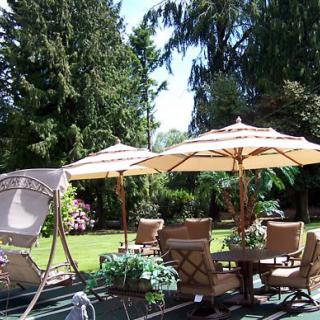 A peaceful garden setting with umbrellas and outdoor furniture surrounded by lush greenery.