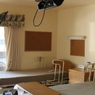 An empty hospital room with beds and medical equipment.