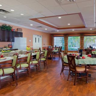 A spacious dining room with neatly arranged tables and chairs, featuring large windows and wooden flooring.