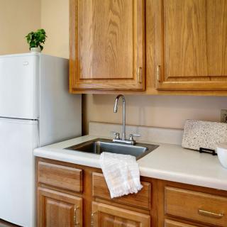 A cozy kitchen corner with wooden cabinets, a fridge, and a sink.