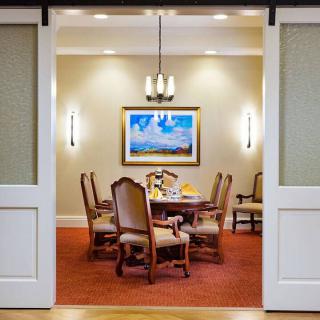 A well-appointed dining room featuring elegant chairs, a central table set for a meal, and artwork on the wall.