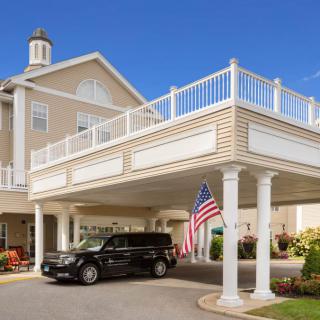 A building entrance with a covered driveway, featuring columns and an American flag.