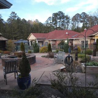 A peaceful residential garden featuring landscaped paths, potted plants, and seating areas.