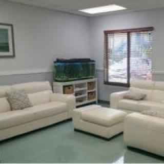 A modern living room with white sofas and a fish tank.