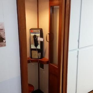 A vintage-style phone booth featuring a public payphone.