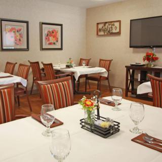 An elegantly decorated dining room with neatly arranged tables and chairs, featuring artwork on the walls.