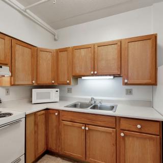 A kitchen with wooden cabinets, a microwave, and a double sink.