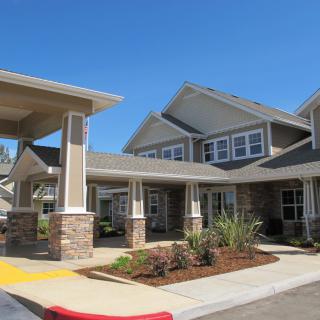 A modern residential building with well-maintained landscaping and a clear blue sky.