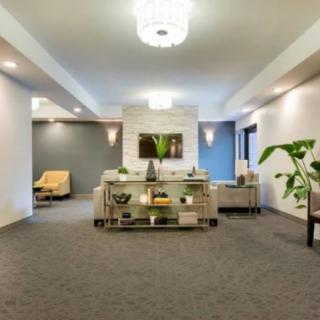 A modern and stylish lobby with contemporary furniture and decor, featuring a central reception desk and decorative plants.