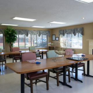 A spacious and well-lit community room with tables and chairs arranged for gatherings or activities.