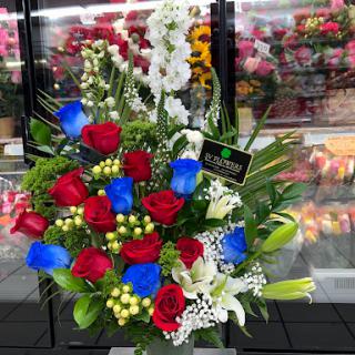 A vibrant floral bouquet featuring a striking combination of red, blue, and white flowers.