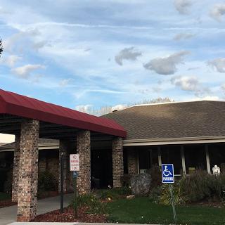 A view of a building featuring a red awning and stone pillars, set against a cloudy sky.