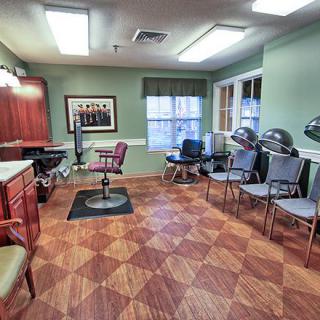 A brightly lit hair salon interior featuring chairs and hairdryers, with a stylish wooden floor.