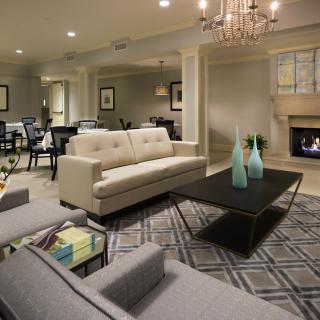 A modern living room with a neutral color scheme, featuring a sofa, coffee table, and fireplace.