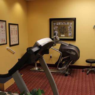 A small gym with exercise equipment, including a treadmill and other fitness machines.