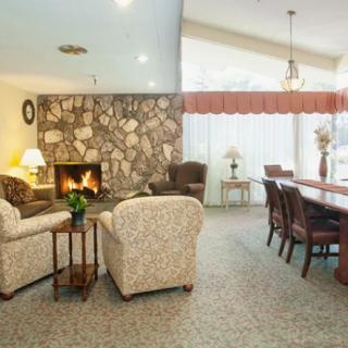 A cozy living and dining area featuring a stone fireplace, comfortable armchairs, and a large dining table.