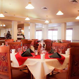 An elegantly set dining area in a restaurant, featuring round tables with red and white tablecloths and neatly arranged chairs.