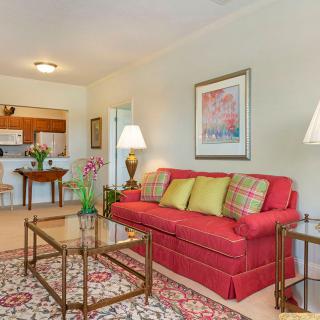 A cozy living room with a red sofa, glass coffee tables, and decorative lamps.