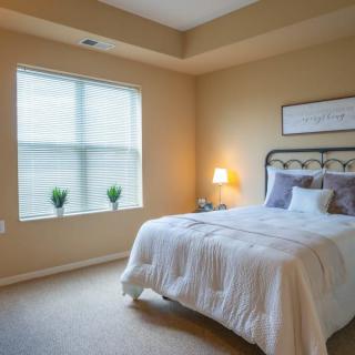 A cozy bedroom with a neatly made bed, soft lighting, and minimalist decor.