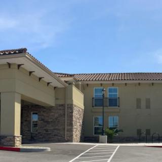 A modern hotel building with a large entrance and an adjacent parking area.