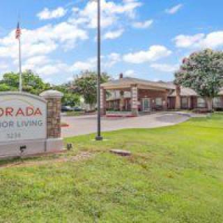 Entrance of a senior living facility with a visible sign and landscaped surroundings.