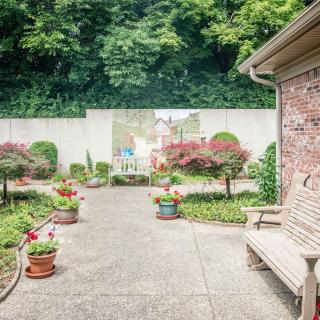 A tranquil garden patio with potted plants and a wooden bench.