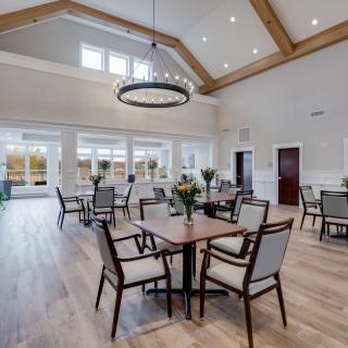 A spacious and elegantly designed dining area featuring modern furniture and a large chandelier.