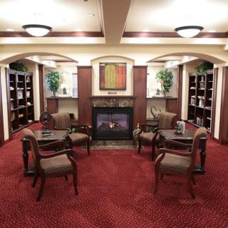 A cozy library with seating area, fireplace, and bookshelves.