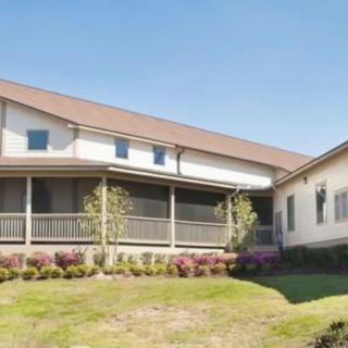A suburban residential house with a large porch and landscaped front yard.