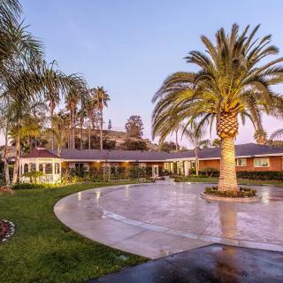 A beautiful house with a large driveway and palm trees at sunset.