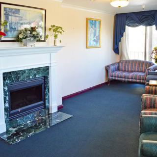 A cozy living room featuring a marble fireplace, comfortable sofas, and elegant decor.