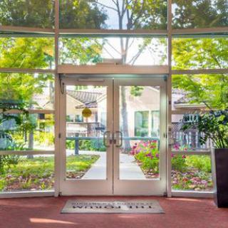 View through glass doors to a garden pathway surrounded by trees.