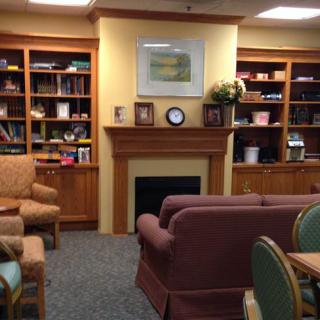 A cozy library room with a fireplace, bookshelves, and comfortable seating.