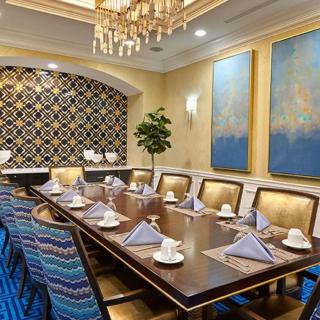 An elegantly decorated dining room with a large table set for a formal gathering, featuring a chandelier and decorative artwork.
