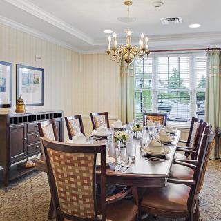 A formal dining room with a long table, elegant chairs, and a chandelier.