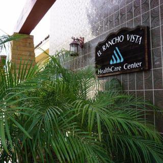 Entrance to El Rancho Vista Healthcare Center surrounded by lush greenery.