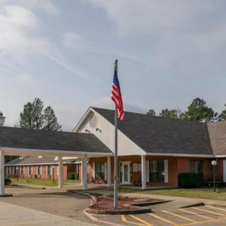 A single-story building with an American flag on a flagpole in the parking lot.