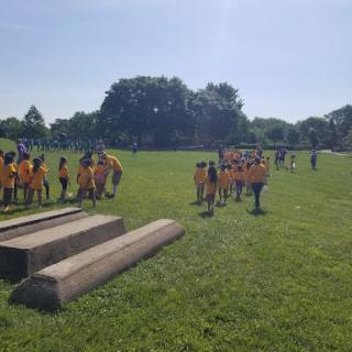 A group of children in yellow shirts enjoying outdoor activities on a sunny day.