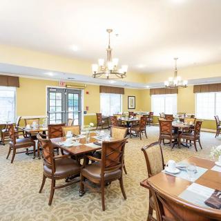 A spacious dining room with neatly arranged tables and chairs, illuminated by chandeliers.