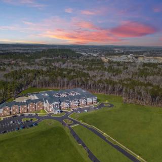 Aerial view of a modern building complex surrounded by lush greenery and a vibrant sunset.