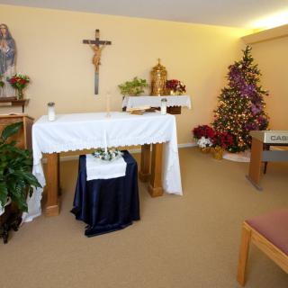 A small chapel with an altar, a cross on the wall, and a decorated Christmas tree.