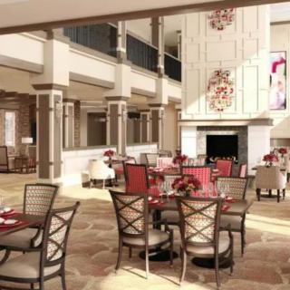 An elegant and spacious restaurant interior with modern furniture and chandeliers, creating an inviting dining atmosphere.