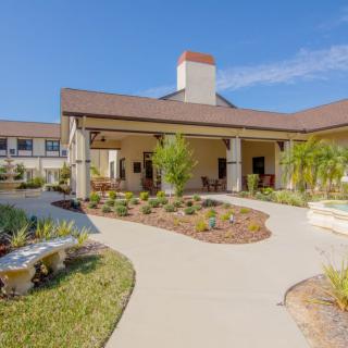 A modern building with a landscaped garden and pathway under a clear blue sky.