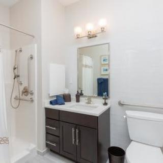 A modern bathroom with a shower, sink, and toilet.