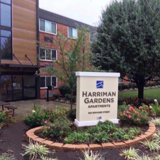 Entrance sign for Harriman Gardens Apartments, surrounded by lush landscaping.